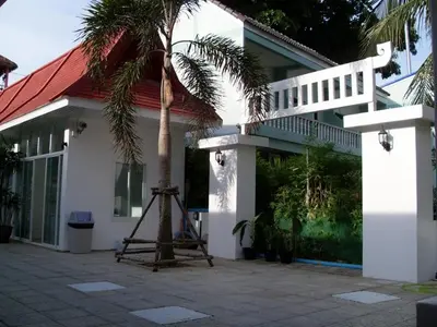 a palm tree in front of a building with a ladder at Clear House Phuket in Kamala Beach