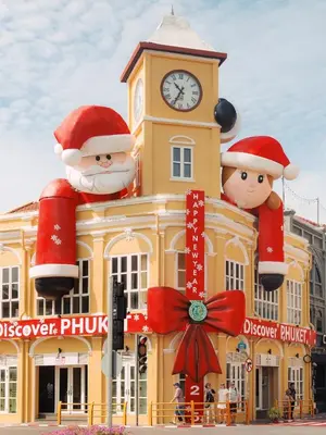 a yellow building with a clock tower with santa hats on it at Royal Phuket City Hotel in Phuket Town