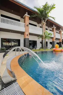 a pool with a water fountain in front of a building at ETK Patong Resort in Patong Beach