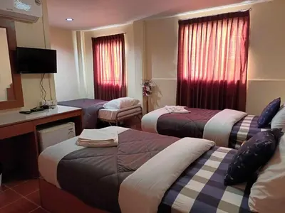 a hotel room with three beds and a television at Patong Rose Guest House 50m to Beach in Patong Beach