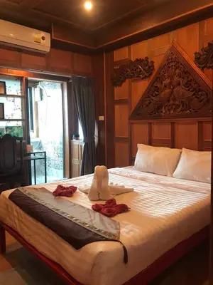 a bedroom with a large bed with two roses on it at Baan Ratchapruek in Phuket Town