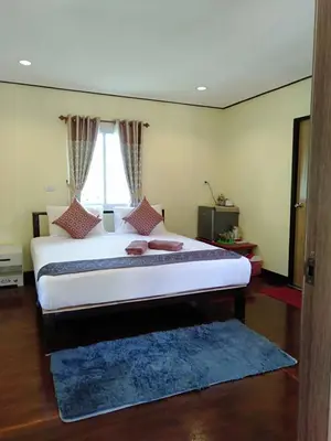 a bedroom with a large bed with a blue rug at Mookdaman Bungalow in Ko Yao Noi