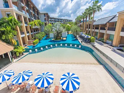 a swimming pool with chairs and umbrellas in a resort at Rawai Palm Beach Resort - SHA Extra Plus in Rawai Beach