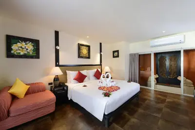 a bedroom with a large white bed and a couch at Andaman White Beach Resort - SHA Plus in Nai Thon Beach