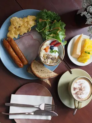 a plate of food with meat and bread and a cup of coffee at Two Villas HOLIDAY - ONYX Style Naiharn Beach, Phuket in Nai Harn Beach