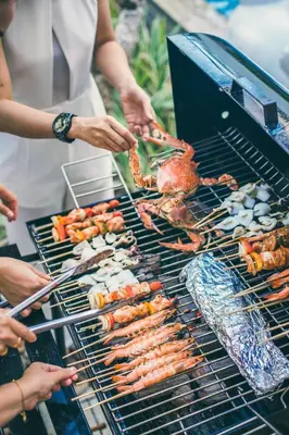 a group of people cooking food on a grill at Two Villas HOLIDAY - ONYX Style Naiharn Beach, Phuket in Nai Harn Beach