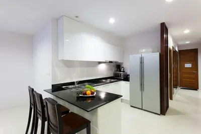 a kitchen with a black counter and a refrigerator at The Park Surin Serviced Apartments by RESAVA in Surin Beach