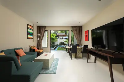 a living room with a couch and a television and a table at Tea Tree Boutique Resort in Rawai Beach