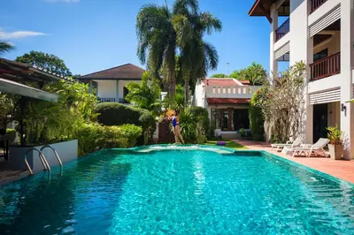 a woman standing next to a swimming pool in a house at Phuket Monaburi Boutique Hotel in Rawai Beach