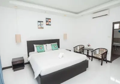 a white bedroom with a bed and a table and chairs at Phuket Monaburi Boutique Hotel in Rawai Beach