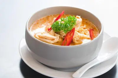 a bowl of soup on a plate with a spoon at Flora Ville-SHA PLUS in Chalong
