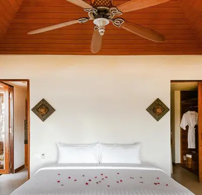 a bedroom with a ceiling fan and a bed at Korsiri Pool Villas in Panwa Beach