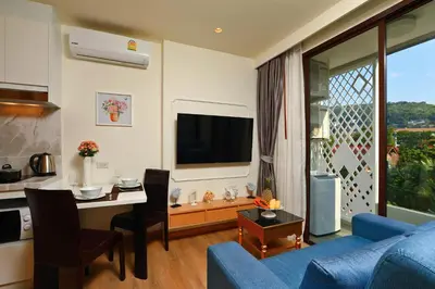 a living room with a blue couch and a tv at Cute Studio in Aristo Beach condo - 7 min walk to Surin Beach, construction view in Surin Beach