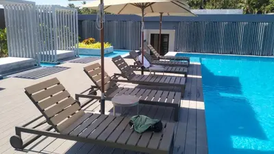 three chairs and an umbrella next to a swimming pool at The Aristo Beach by Holy Cow, studio, without kitchen, construction view in Surin Beach
