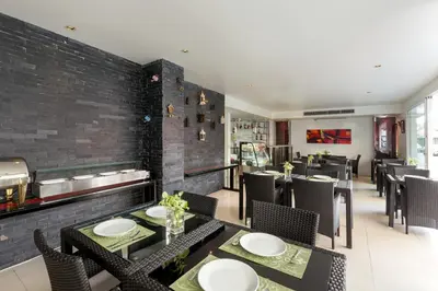 a restaurant with tables and chairs and a brick wall at Grand Sunset Hotel Phuket in Karon Beach
