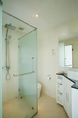 a bathroom with a glass shower and a sink at Grand Sunset Hotel Phuket in Karon Beach