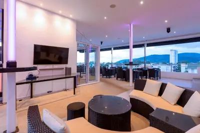 a living room with a couch and a tv at Grand Sunset Hotel Phuket in Karon Beach
