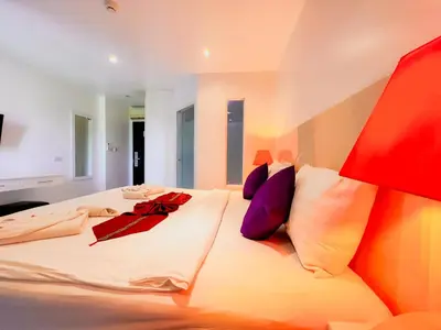 a bedroom with a large white bed with purple pillows at Grand Sunset Hotel Phuket in Karon Beach