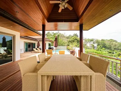 a dining room with a table and chairs on a deck at Villa Tantawan Resort - Private Pool Villas in Kamala Beach