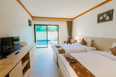 a hotel room with two beds and a flat screen tv at Airport Beach Hotel Phuket in Nai Yang Beach