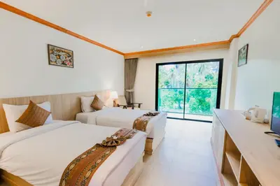 two beds in a room with a window at Airport Beach Hotel Phuket in Nai Yang Beach