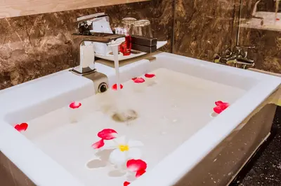 a sink with flower petals in the water at Airport Beach Hotel Phuket in Nai Yang Beach