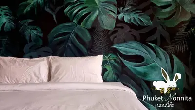 a bedroom with a bed with a mural of plants at Phuket Nonnita Boutique Resort - SHA Plus in Phuket Town