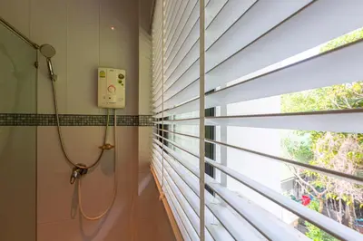a bathroom with a shower and a window with blinds at Rossarin Sea View Patong in Patong Beach