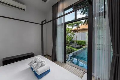 a bedroom with a bed with towels and a pool at VILLA ARU Private Pool 3 min to Naiharn Beach in Nai Harn Beach