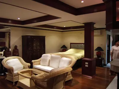 a bedroom with a bed and wicker chairs at Prince Edouard Apartments & Resort Patong Beach Phuket in Patong Beach