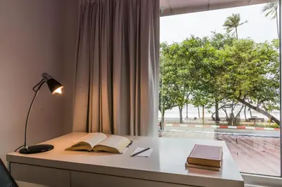 a desk with two books and a lamp and a window at The L Resort, Krabi in Ao Nang Beach