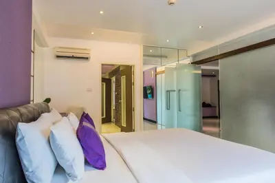 a bedroom with a large bed with purple and white pillows at The L Resort, Krabi in Ao Nang Beach