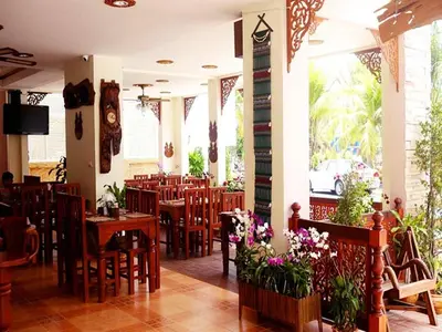 a restaurant with wooden tables and chairs and flowers at The Orchid House - SHA Extra Plus in Kata Beach