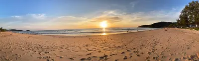 a beach with the sun setting on the water at Phuket Golden Sand Inn - SHA Extra Plus in Karon Beach