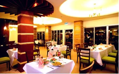 a restaurant with white tables and chairs with food on them at Kalim Resort in Patong Beach