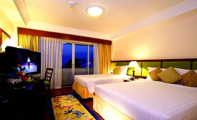 a hotel room with two beds and a television at Kalim Resort in Patong Beach