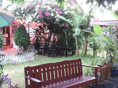 a wooden bench in a garden with flowers and plants at Blue Paradise Residence in Rawai Beach