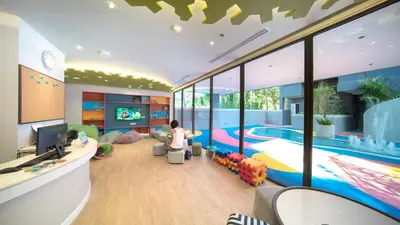 a woman sitting in a living room with a swimming pool at The Nature Phuket in Patong Beach