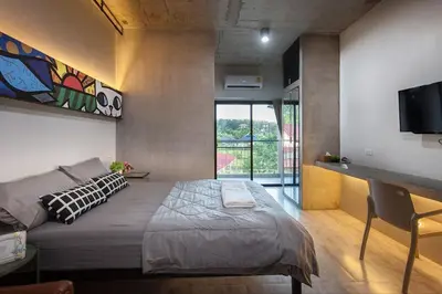 a bedroom with a bed and a table and a tv at Be Live Residence in Thalang