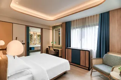 a hotel room with a bed and a chair at Dusit Thani Krabi Beach Resort in Klong Muang Beach