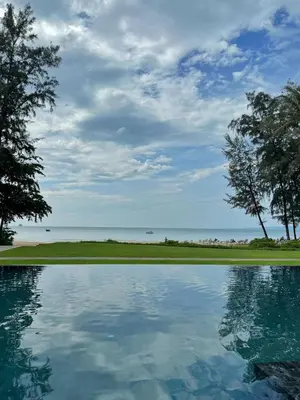 a pool of water with trees and the ocean at Dusit Thani Krabi Beach Resort in Klong Muang Beach