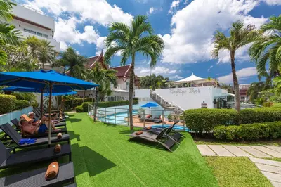 a resort with a pool with people laying on chairs and umbrellas at Phunawa Resort Phuket Karon Beach in Karon Beach