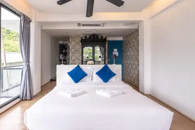 a bedroom with a large white bed with blue pillows at See Sea Villa Phuket SHA in Patong Beach