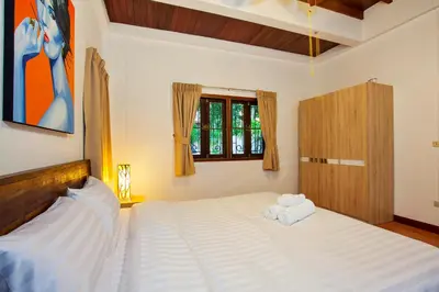 a bedroom with a bed with two towels on it at Traditional Thai Villa Nikkie in Tropical Nature, 4BR & Pool, near Rawai Beach in Nai Harn Beach