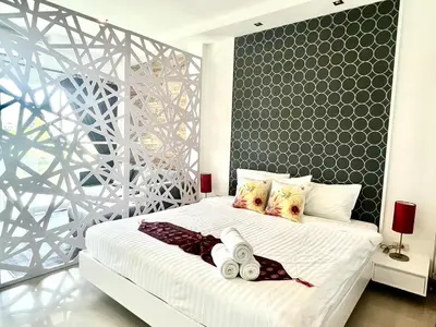 a bedroom with a large white bed with a black wall at Sivana Place Phuket in Bang Tao Beach