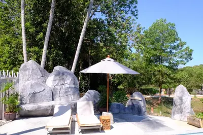 a couple of chairs and an umbrella next to some rocks at Awana Villa Resort Yaonoi - SHA Extra Plus in Ko Yao Noi