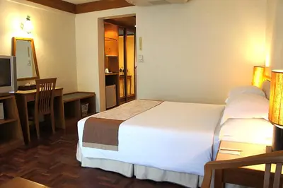 a hotel room with a large bed and a desk at Safari Beach Hotel Patong in Patong Beach