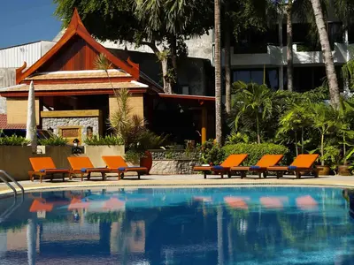 a group of orange chairs sitting next to a swimming pool at Safari Beach Hotel Patong in Patong Beach