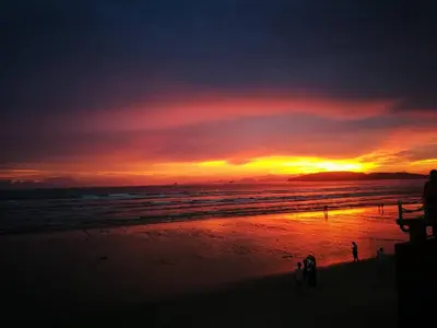 a sunset at the beach with people walking on the beach at Seaworld Guesthouse in Ao Nang Beach