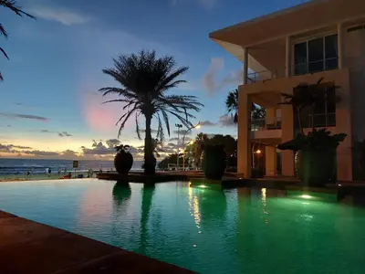 a house with a swimming pool in front of the ocean at Karon Sea View Beach Apartment in Karon Beach